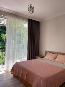 um quarto com uma cama e uma grande janela em Guest House My Home em Gonio