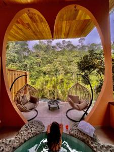 a woman laying in a tub in a room with a heart shaped window at Saguamby Mindo Lodge in Mindo