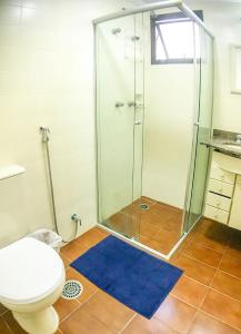 een badkamer met een douche, een toilet en een blauw tapijt bij Otimo Apto a 200m - Praia das Pitangueiras Guaruja in Guarujá
