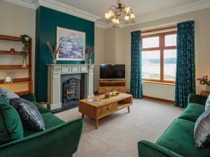 a living room with green furniture and a fireplace at Kringlands in Stranraer