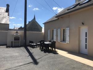 een patio met een tafel en stoelen naast een gebouw bij Le paradis d'Alice in Le Molay-Littry
