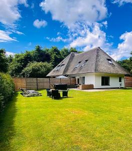a house with a grassy yard with a picnic table at The island life texel met jacuzzi in De Koog