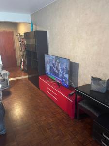 uma sala de estar com uma televisão de ecrã plano num centro de entretenimento vermelho em Studio Élysées em Paris