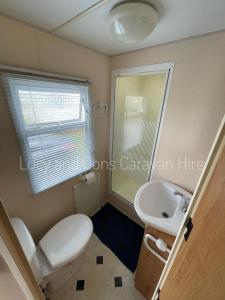 uma casa de banho com um WC branco e um lavatório. em Mablethorpe Seaside Holiday Home em Mablethorpe