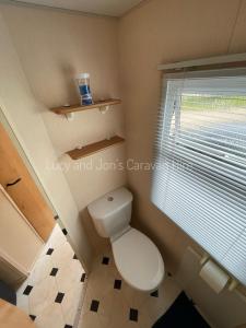 uma pequena casa de banho com um WC e uma janela em Mablethorpe Seaside Holiday Home em Mablethorpe