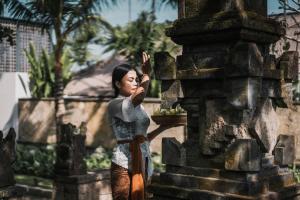 a woman standing in front of a stone building at Kharista Villas & Retreat by Ekosistem in Canggu