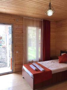 a bedroom with a bed and a large window at Cottage and Gigo Papa's Wine Cellar in Kvareli