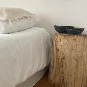 1 cama con sábanas blancas y 2 tazones sobre un tocón de madera en la boutique mj décoration vous propose de découvrir ses deux chambres d'hôtes en Doué-la-Fontaine