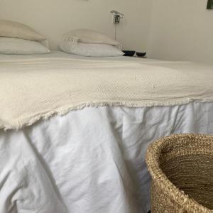 uma cama com lençóis brancos e um gato sentado ao seu lado em la boutique mj décoration vous propose de découvrir ses deux chambres d'hôtes em Doué-la-Fontaine