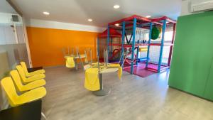 een speelkamer met gele stoelen en een speeltuin bij Apartamentos Elegance El Conserje in Denia