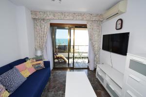 a living room with a blue couch and a flat screen tv at BENIBEACH - Fincas Arena in Benidorm