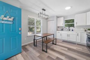 cocina con mesa y puerta azul en NEW Modern Bungalow Close to Downtown! Fully Fenced Yard, en St. Augustine