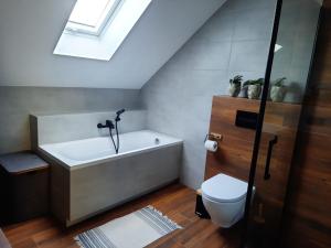 a bathroom with a bath tub and a toilet at Uroczy apartament z dostępnym parkingiem i ogrodem in Szczytniki