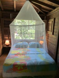 uma cama com uma rede mosquiteira num quarto em mon Ecolodge Creole em Fort-de-France