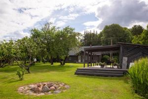 Newly renovated Latvian farm house في Kraujas: منزل مع حفرة نار في ساحة
