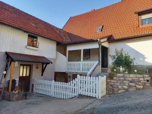 una casa bianca con un tetto arancione e una recinzione bianca di Ferienwohnung am Schwedenberg , Trimberg a Elfershausen