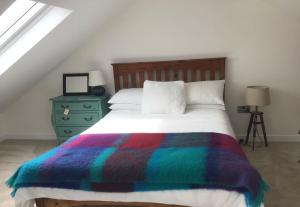 a bedroom with a bed with a colorful blanket on it at The Birdhouse with Hot Tub in Gortahork