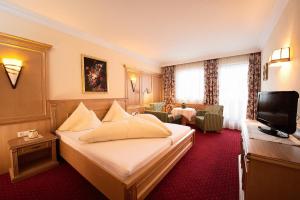 a hotel room with a bed and a television at Hotel Eschenhof & Apartments in Fulpmes