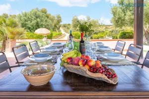 einen Tisch mit einer Schale Obst und Weinflaschen in der Unterkunft URI - Guest House Tenute Shardana in 