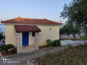 una pequeña casa blanca con una puerta azul en Iliadis Vacation Homes en Petalídhion