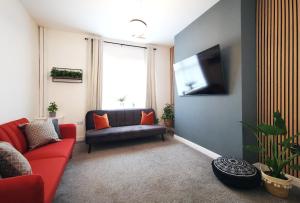 a living room with a red couch and a flat screen tv at The Mellor - Holiday Home 15 Mins to Central Manchester With Free Parking in Manchester