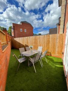 um pátio com uma mesa e cadeiras na relva em Stunning New Townhouse in the Heart of Warwick em Warwick