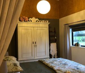 ein Schlafzimmer mit einem weißen Schrank und einem Fenster in der Unterkunft Cosy Country Stay B&B in Matamata