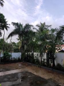 a courtyard with palm trees and a white fence at Park Grand Boutique 3 Bedroom Bungalow in Marmagao