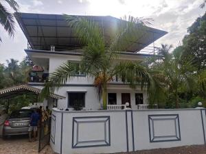 ein weißes Haus mit einer Palme davor in der Unterkunft Park Grand Boutique 3 Bedroom Bungalow in Marmagao