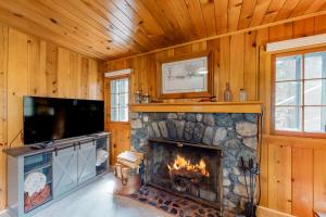 a living room with a fireplace and a flat screen tv at Knotty Pine Cabin in Joseph