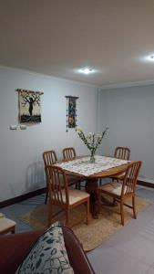 a dining room with a table with chairs and a vase of flowers at Casa en Pingueral 4 in Tomé