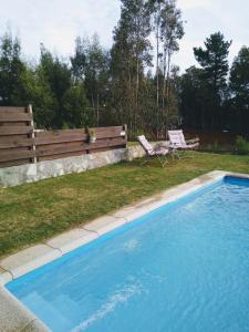 a swimming pool with a bench and a chair at Casa en Pingueral 4 in Tomé