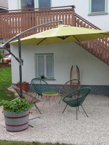 een patio met een tafel en stoelen onder een gele parasol bij Pr' Šovarjo in Zgornje Gorje