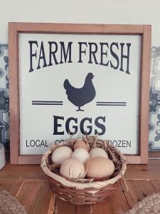 una cesta de huevos delante de un cartel de huevos frescos de granja en Très joli appartement équipé au calme en Rozoy