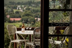 a table with two glasses of wine on a balcony at Viewpoint - Cabin 2 in Haenertsburg