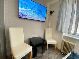 twee stoelen en een tafel in een kamer met een tv bij 24 hour-Self Check-in Apartment Námestie Svätého Egídia in Poprad