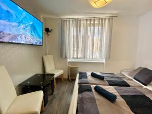 een kamer met 2 bedden, een bureau en een televisie bij 24 hour-Self Check-in Apartment Námestie Svätého Egídia in Poprad