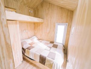 a small bedroom with a bed in a tiny house at Loyca Eco-Tiny House in Balneario El Condor