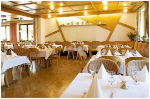 ein Restaurant mit Tischen und Stühlen mit weißem Tischtuch in der Unterkunft Hotel Bayerischer Hof in Lindenberg im Allgäu