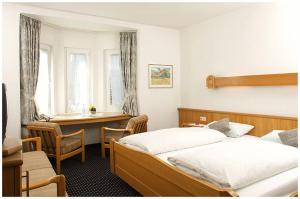 a bedroom with two beds and a desk in it at Hotel Bayerischer Hof in Lindenberg im Allgäu