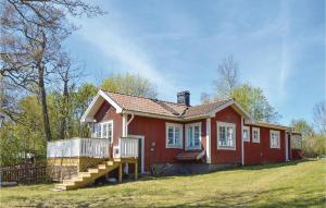 uma casa vermelha com um deque no quintal em Lovely Home In Grdd With Sauna em Gräddö