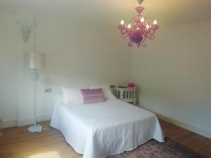 ein Schlafzimmer mit einem weißen Bett und einem Kronleuchter in der Unterkunft Céntrico y amplio piso con plaza parking in Cangas