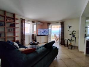 a living room with a blue couch and a television at Apartment Teleferica Rabac in Rabac
