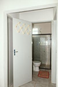 uma casa de banho com WC e uma porta branca em Pousada Riviera - Praia de Lagoa do Pau em Coruripe