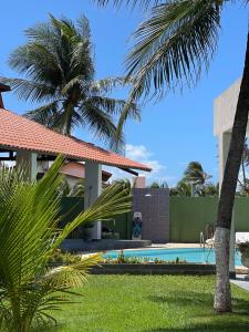 a villa with a swimming pool and palm trees at Pousada Kite Da Mary Cumbuco in Cumbuco
