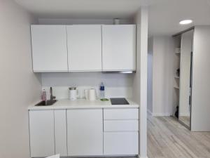 a white kitchen with white cabinets and a sink at Apartamentai įsikūrę Šventojoje in Palanga +13 photos