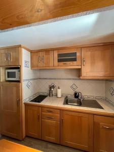uma cozinha com armários de madeira, um lavatório e um micro-ondas em Envalira Vacances - Etoile duplex ideal familia con vista a pistas em Pas de la Casa