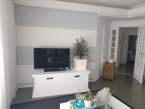 uma sala de estar com televisão numa parede branca em Casa "Vó Minda" - Nazaré - Alojamento Local na Nazaré