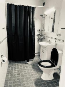 a bathroom with a toilet and a black shower curtain at STAY Matinkatu Apartment in Espoo