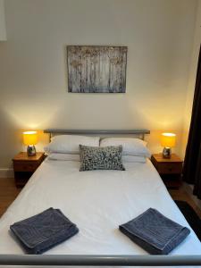 a white bed with two towels on it with two lamps at Cheerful 3 bedroom cottage in central location in Ambleside
